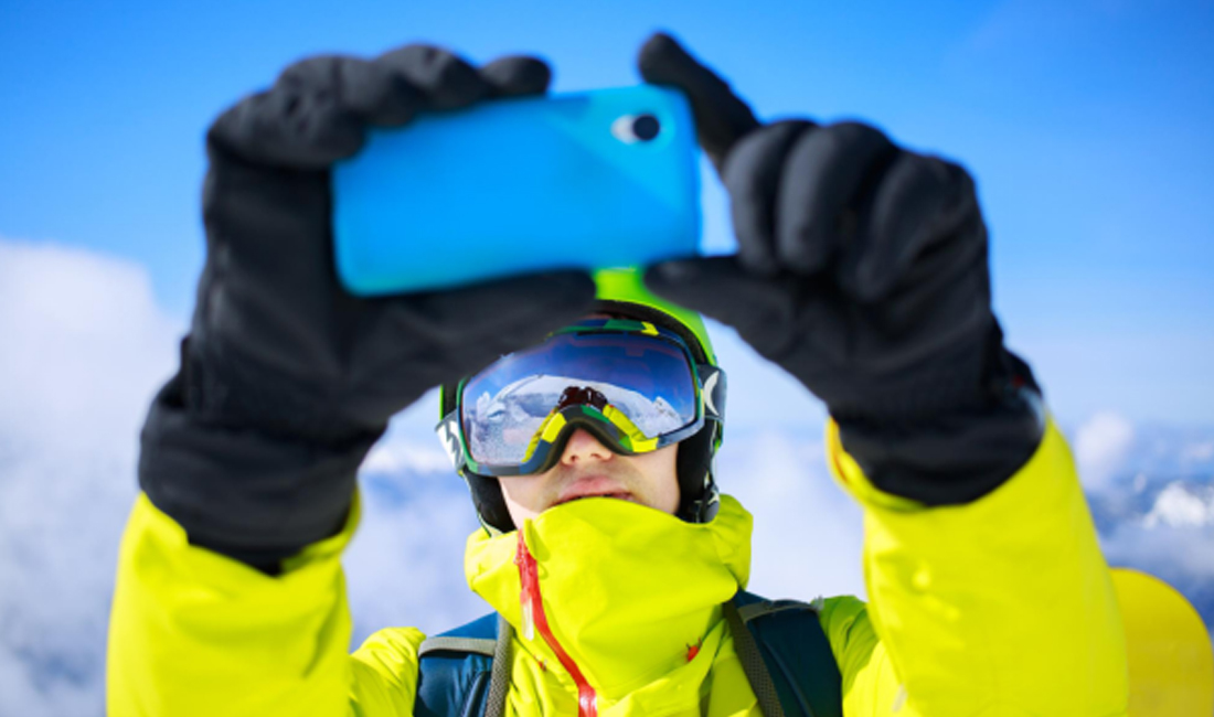 Close-up of gloved hand operating a phone screen outdoors in winter | HANVO