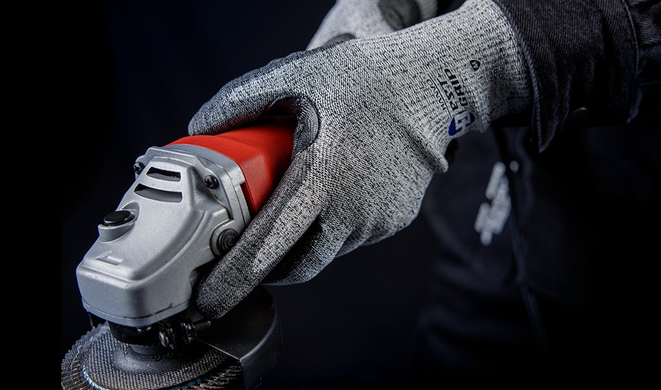 Worker wearing safety gloves handling tools in a manufacturing environment, showcasing proper hand protection practices.